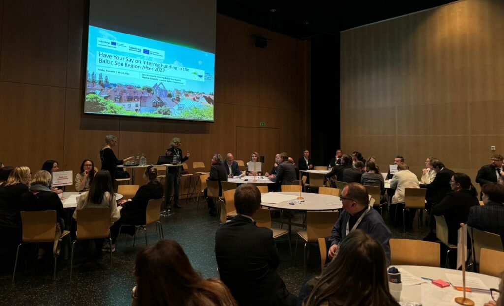 Decorative image from the Interreg funding after 2027 workshop. A group of people in a seminar room with a digital screen in the background. 