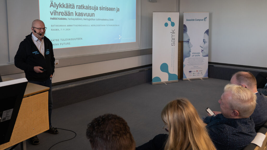 A speaker in a seminar hall with people in the audience