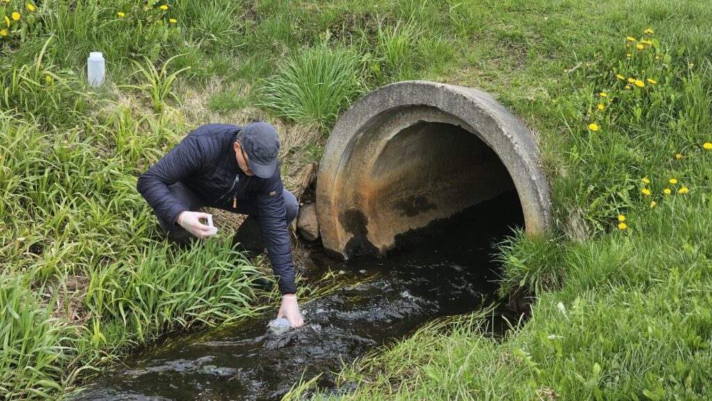 A person collecting a water sample from a ditch in pilot area in Estonia.