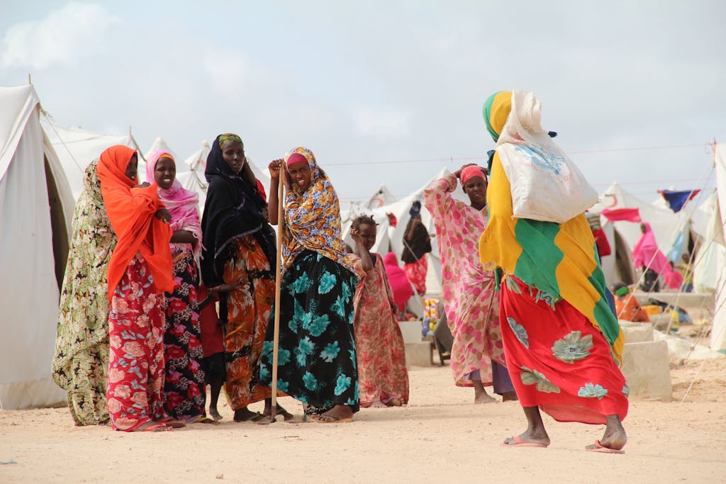 Women in colorful attire gather in Dadaab refugee camp, showcasing vibrant community life.