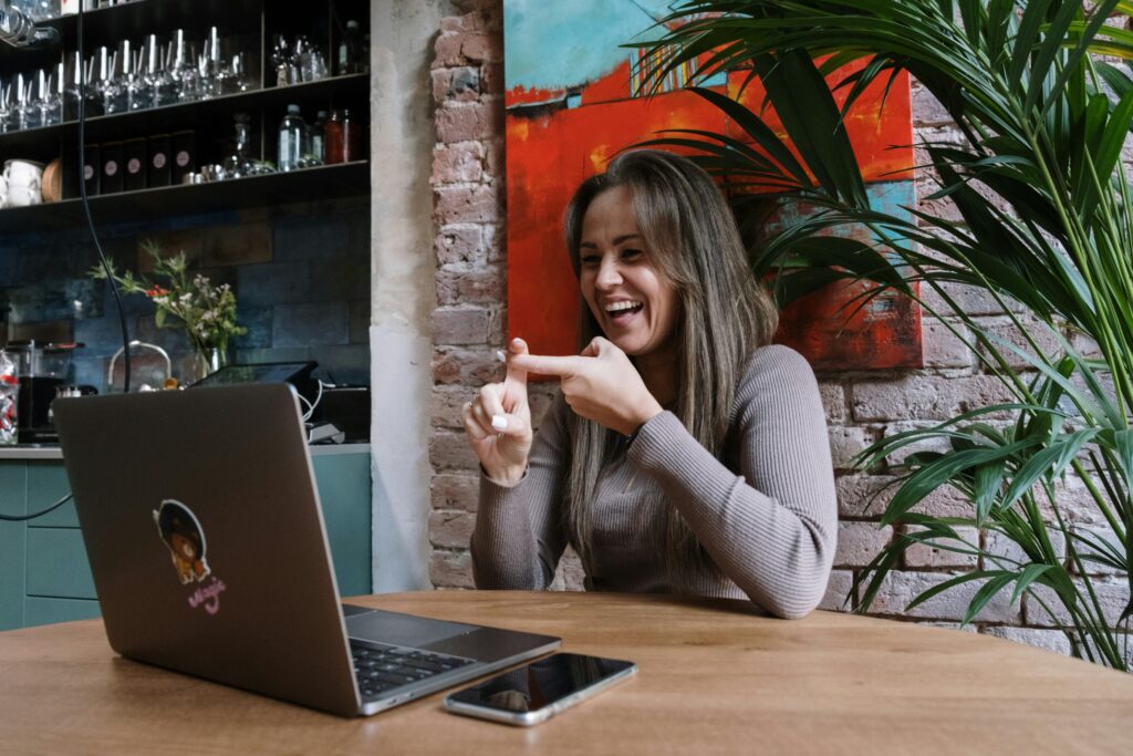 The picture shows happy woman using sign language in front of a laptop