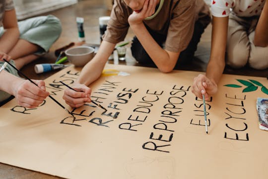 Kids creating a poster on recycling and environmental awareness in an educational setting.