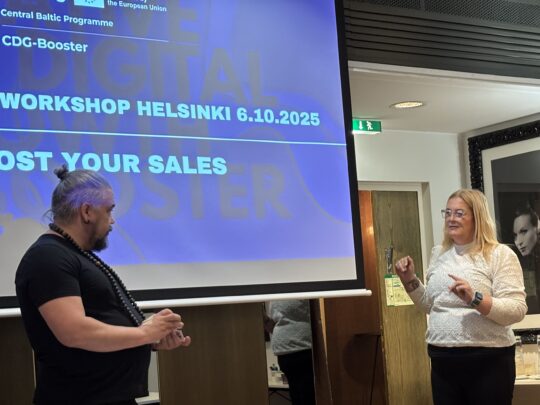 Two people standing in front of a large presentation screen.