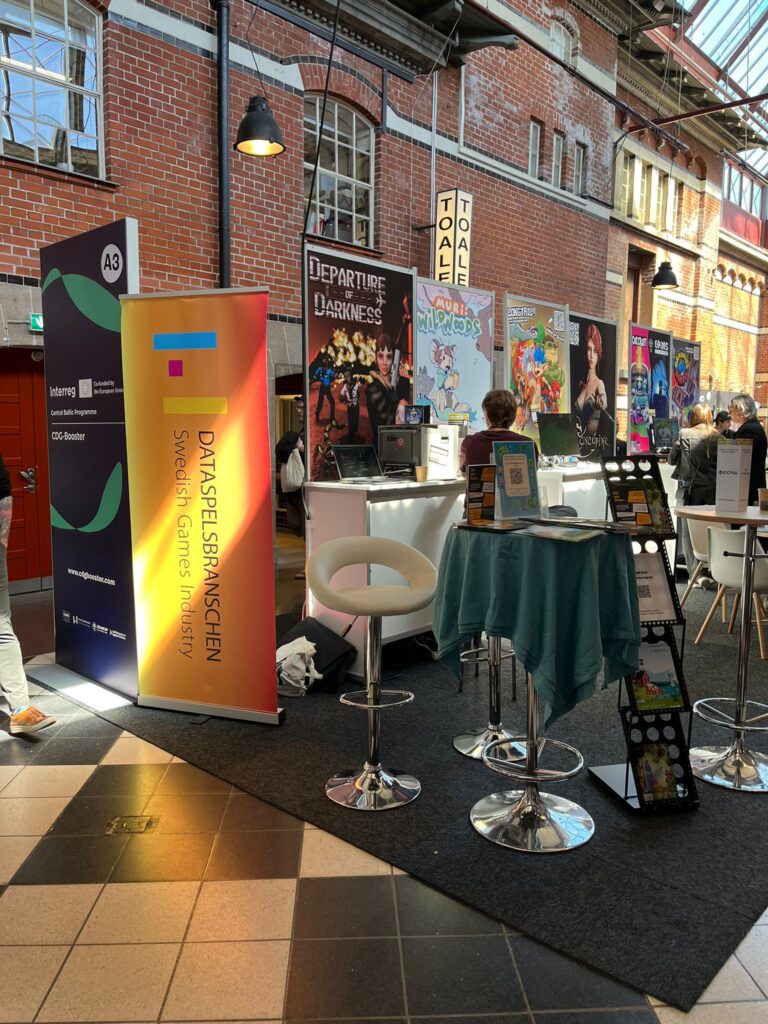 CDG-Booster booth with game demo stations at a conference venue.