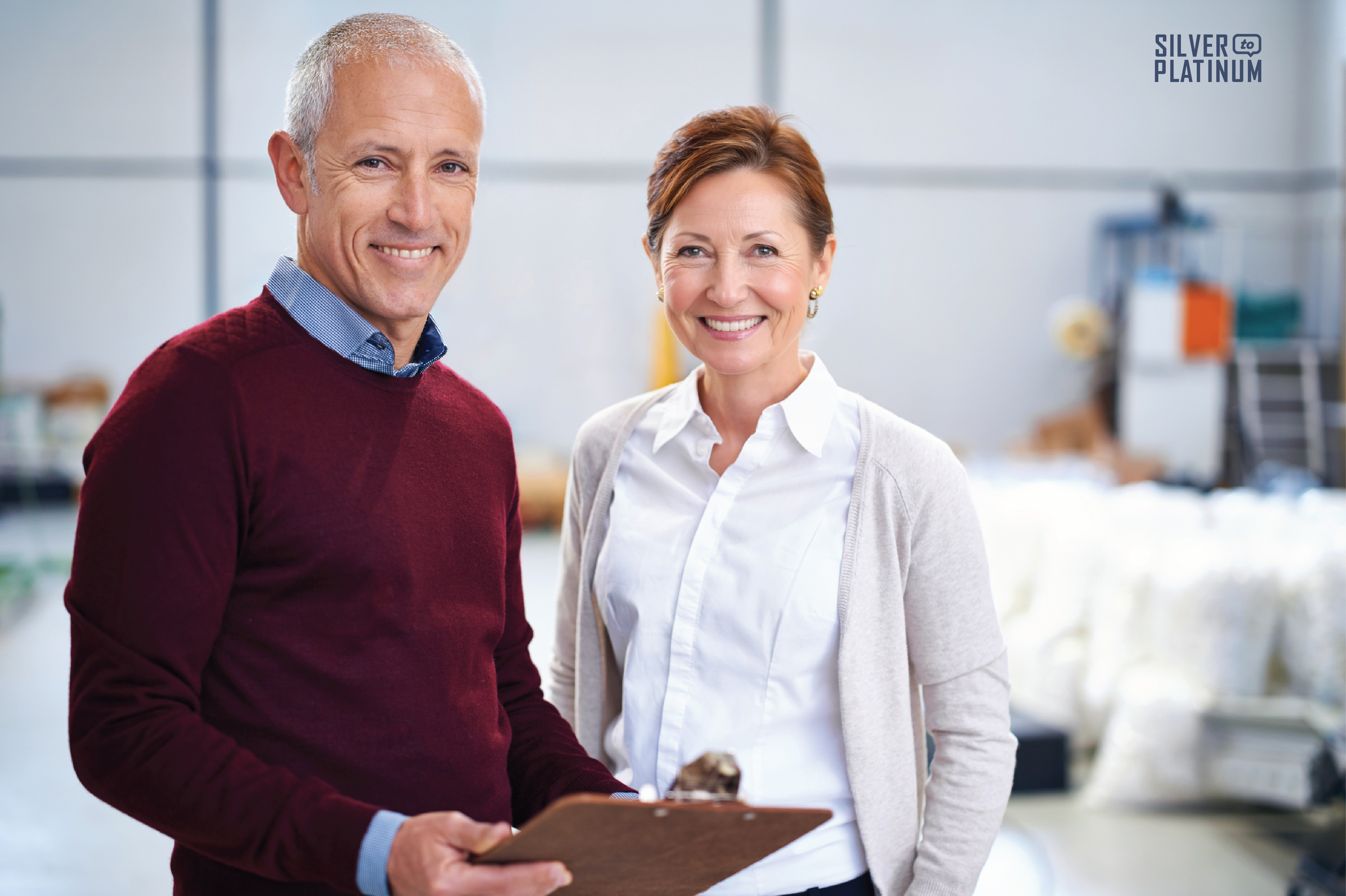 Two employees from different generations standing together in a warehouse