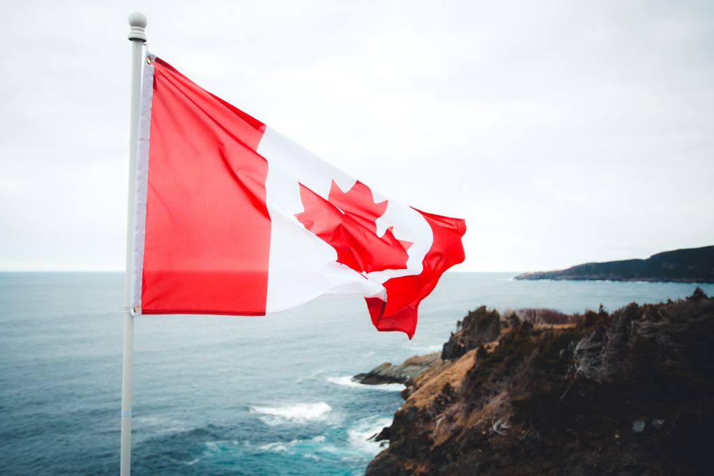 Canadian flag waving over a beautiful, rugged coastline with ocean views.