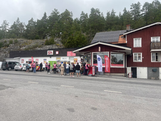Crowd outside Sjöberga general store in Hannäs, where staff in pink vests help residents register in the carpooling app.