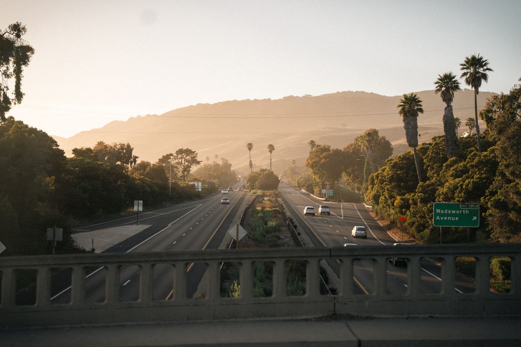 A tranquil highway view with palm trees and sunrise, perfect for travel themes.